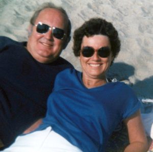 Color photo of a couple smiling on a beach.