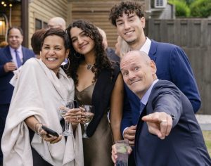 Color photo of a smiling family, dressed formally.