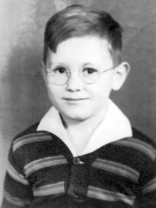 Black and white photo portrait of a young boy in wire-rimmed glasses
