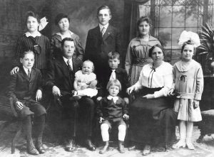 Historical black and white photo of a family of 11, with front row seated and back row of 4 standing.