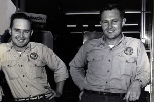 Black and white photo of two smiling men in Gulf gas station uniforms.