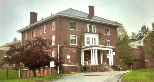 Color photo of a red brick building with a white-columned front entrance.